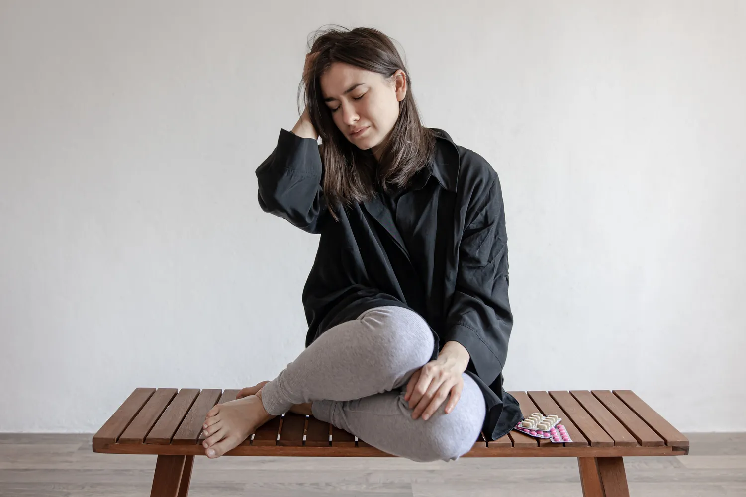 Femme assise sur un banc qui se tient la tête à cause de douleurs chroniques